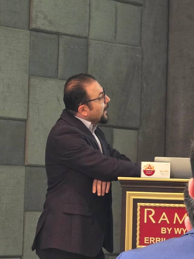 Dr. Karzan leaning on the lectern as he speaks