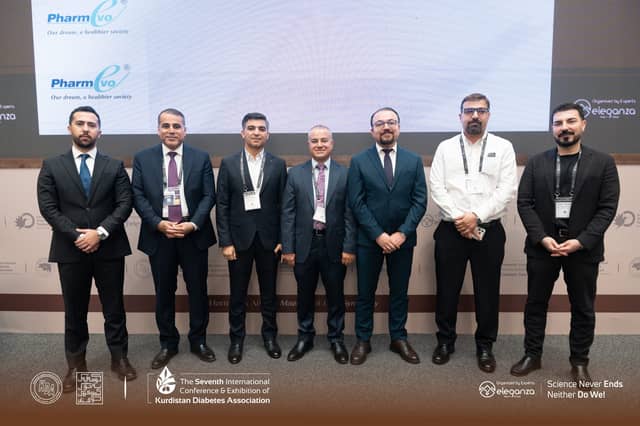 Dr. Karzan with six fellow faculty members in front of the stage screen