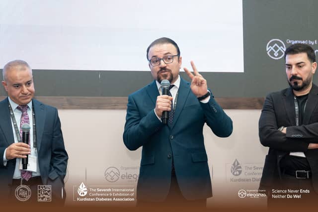 Dr. Karzan holding a microphone and gesturing as he answers