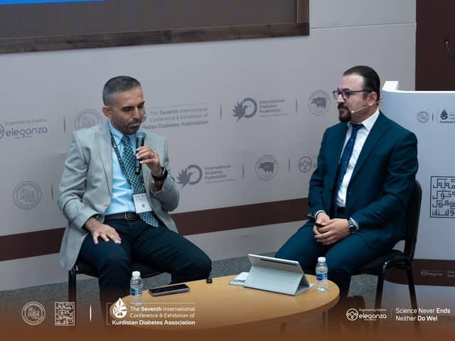 Dr. Karzan seated beside a fellow panellist who is speaking into a microphone